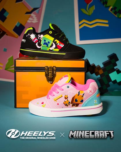 A pair of Heelys x Minecraft shoes displayed on and around an orange pixelated chest. One shoe is black with Creeper graphic patches, and the other is light pink with a white sole and bee graphics.